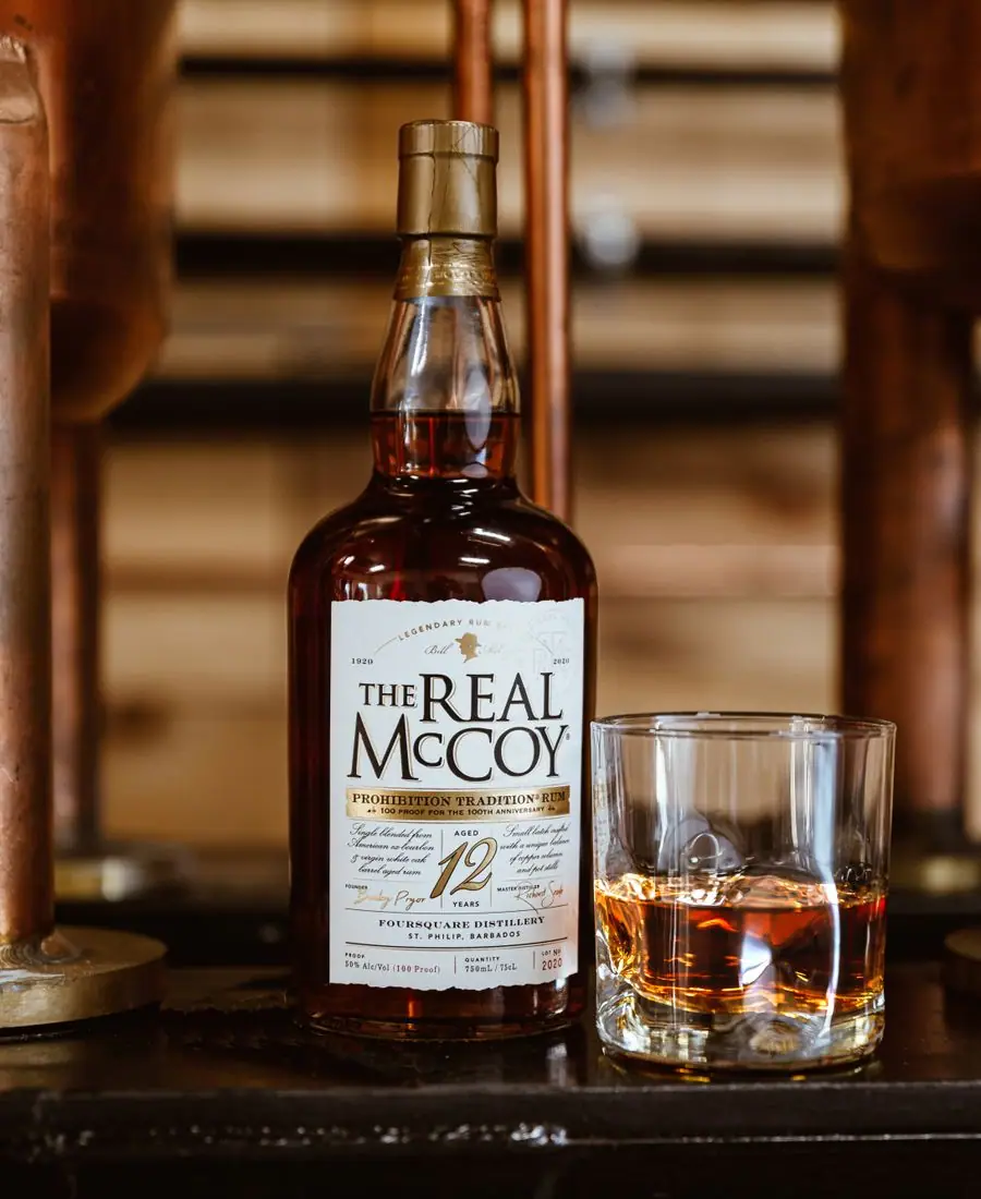 Amber rum bottle with a wax-dipped cork glowing against a dark wood backdrop