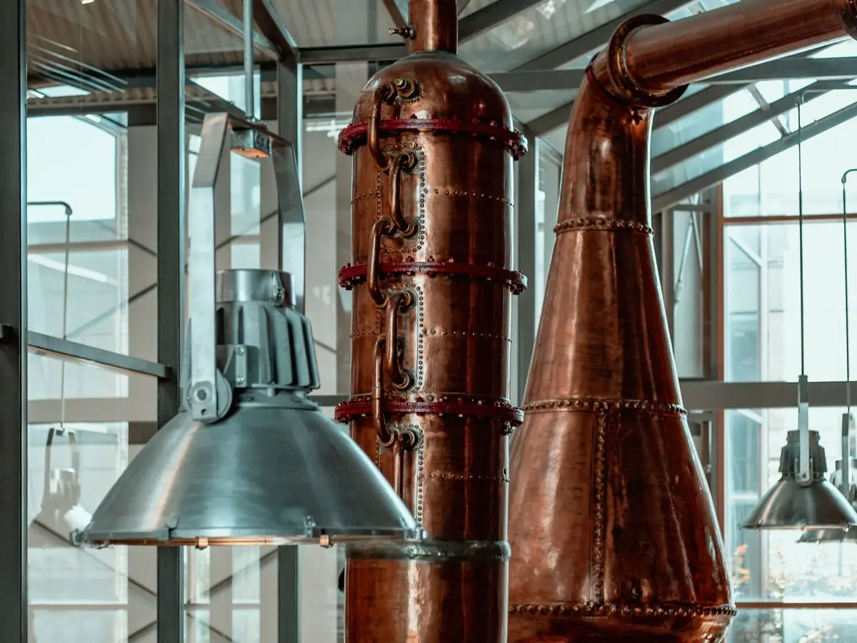 Cozy distillery tasting room with a reclaimed-wood bar, copper accents and a row of spirit bottles on slate shelves